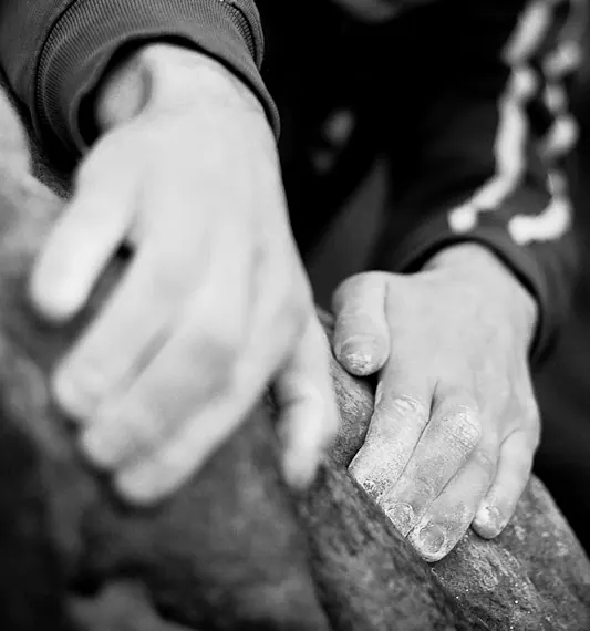 Mains d’un grimpeur sur un bloc de Fontainebleau, en noir et blanc