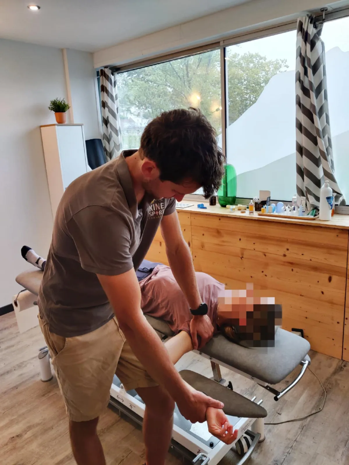 Kinésithérapeute évaluant la rotation externe de l’épaule d’une patiente allongée sur la table